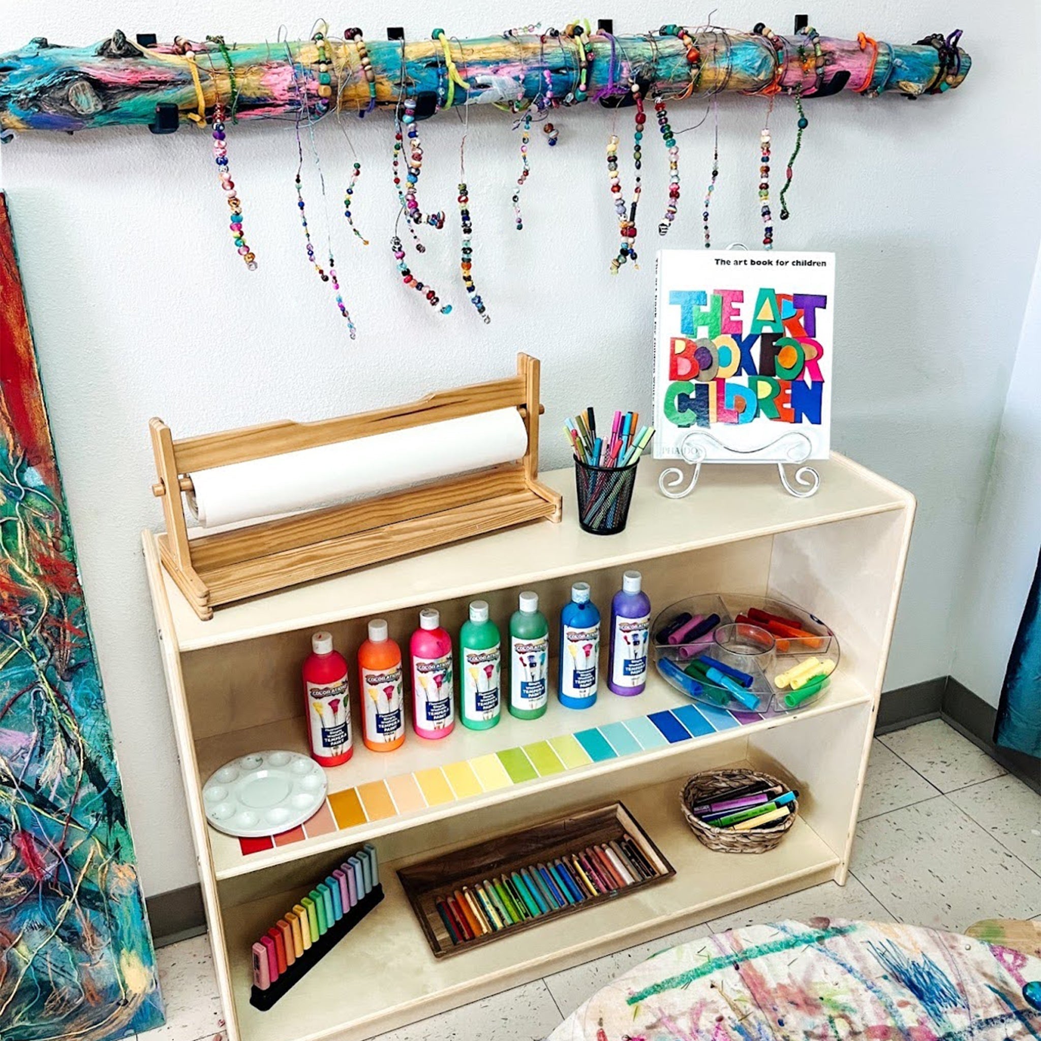 Book shelf with art supplies and handmade wall art hanging an example of a mini atelier