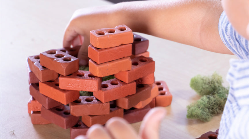 young boy playing with Guidecraft Little Bricks, a natural building toy that makes the perfect holiday gift for kids 3 and up