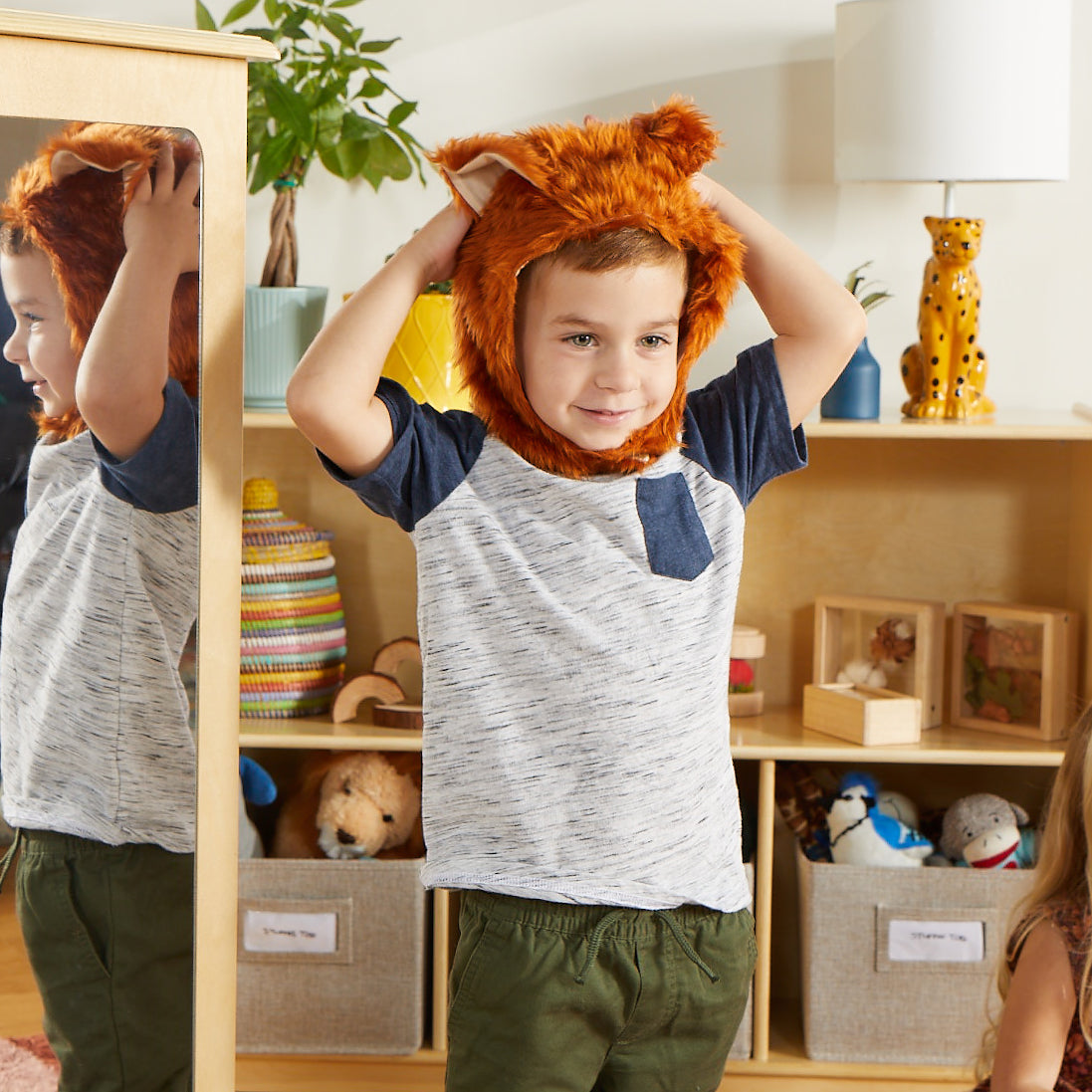Image of a preschool-aged boy wearing an animal costume from the Guidecraft rotating dress up costume storage center. 