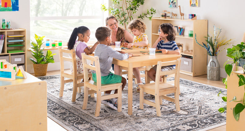 Classroom scene with several children and a teacher making art at a table