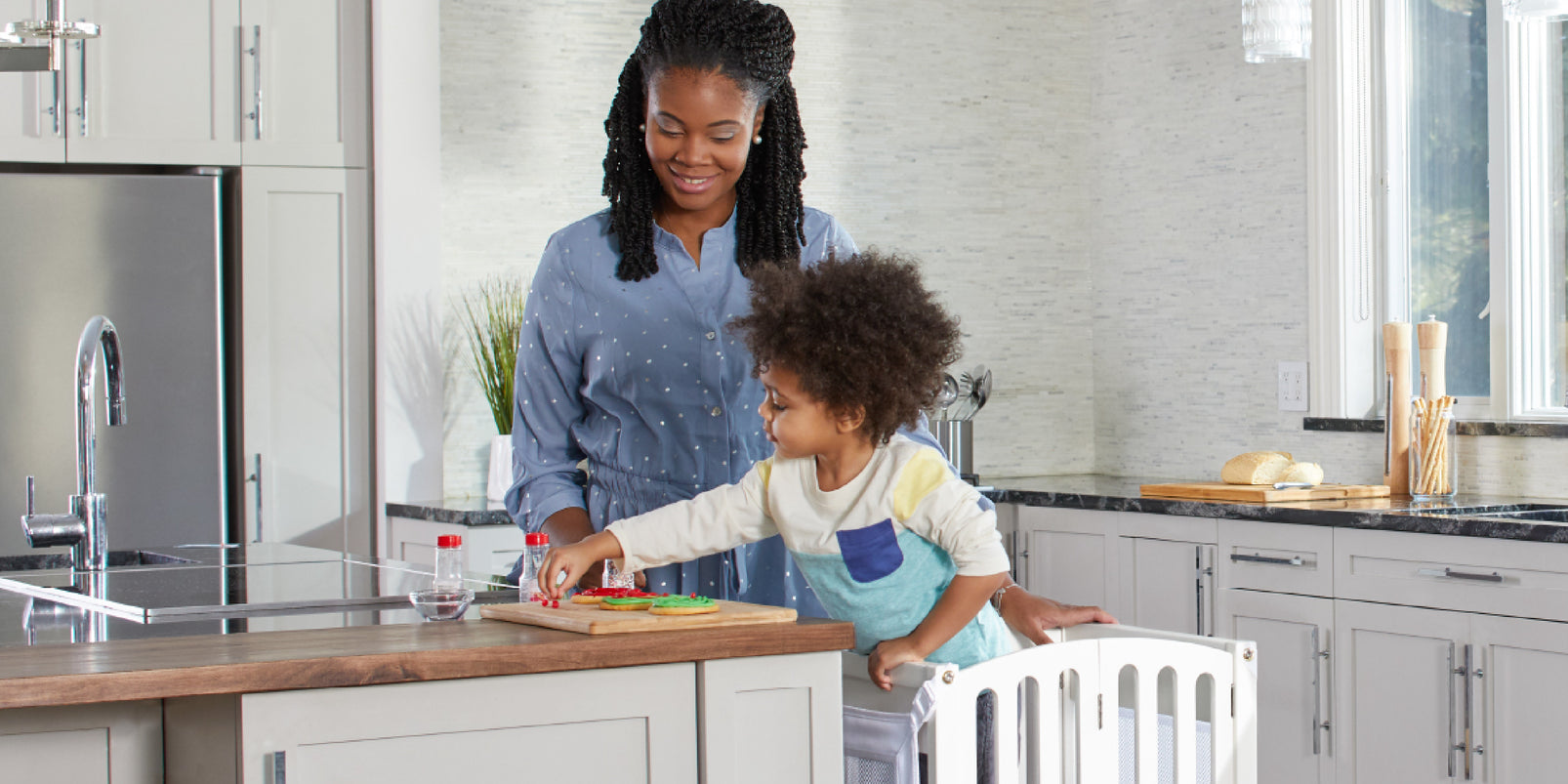 A woman and her young child share a smile while preparing fresh ingredients together in a bright, modern kitchen.