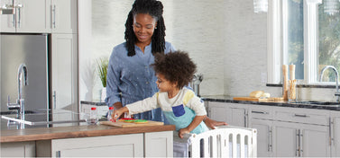 A woman and a young child joyfully decorate cookies together in a bright, modern kitchen, creating sweet memories.