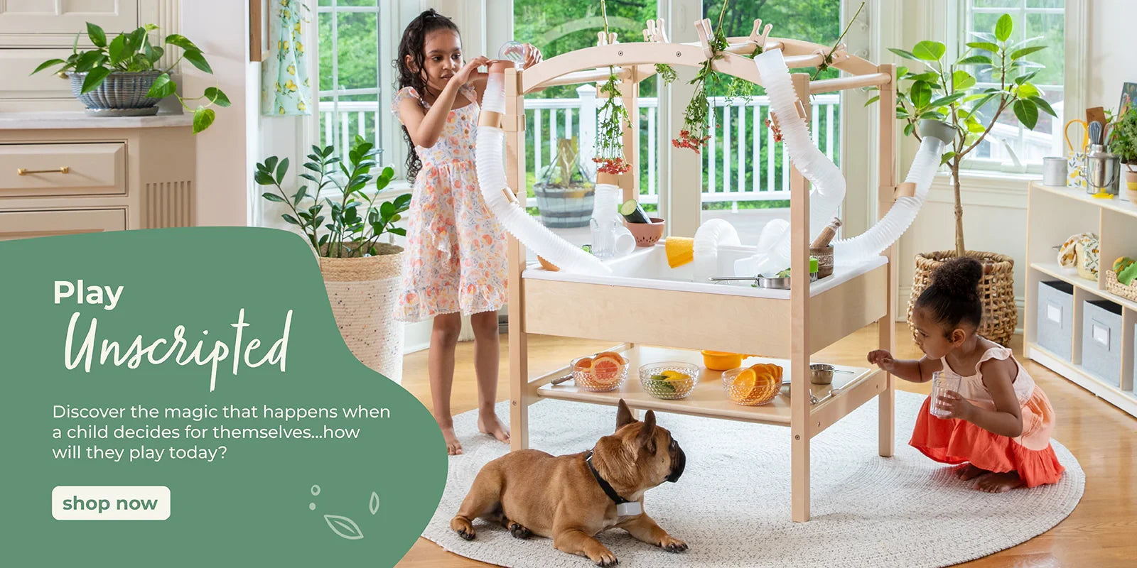 Two young girls play with a wooden activity table indoors as their brown dog rests nearby.
