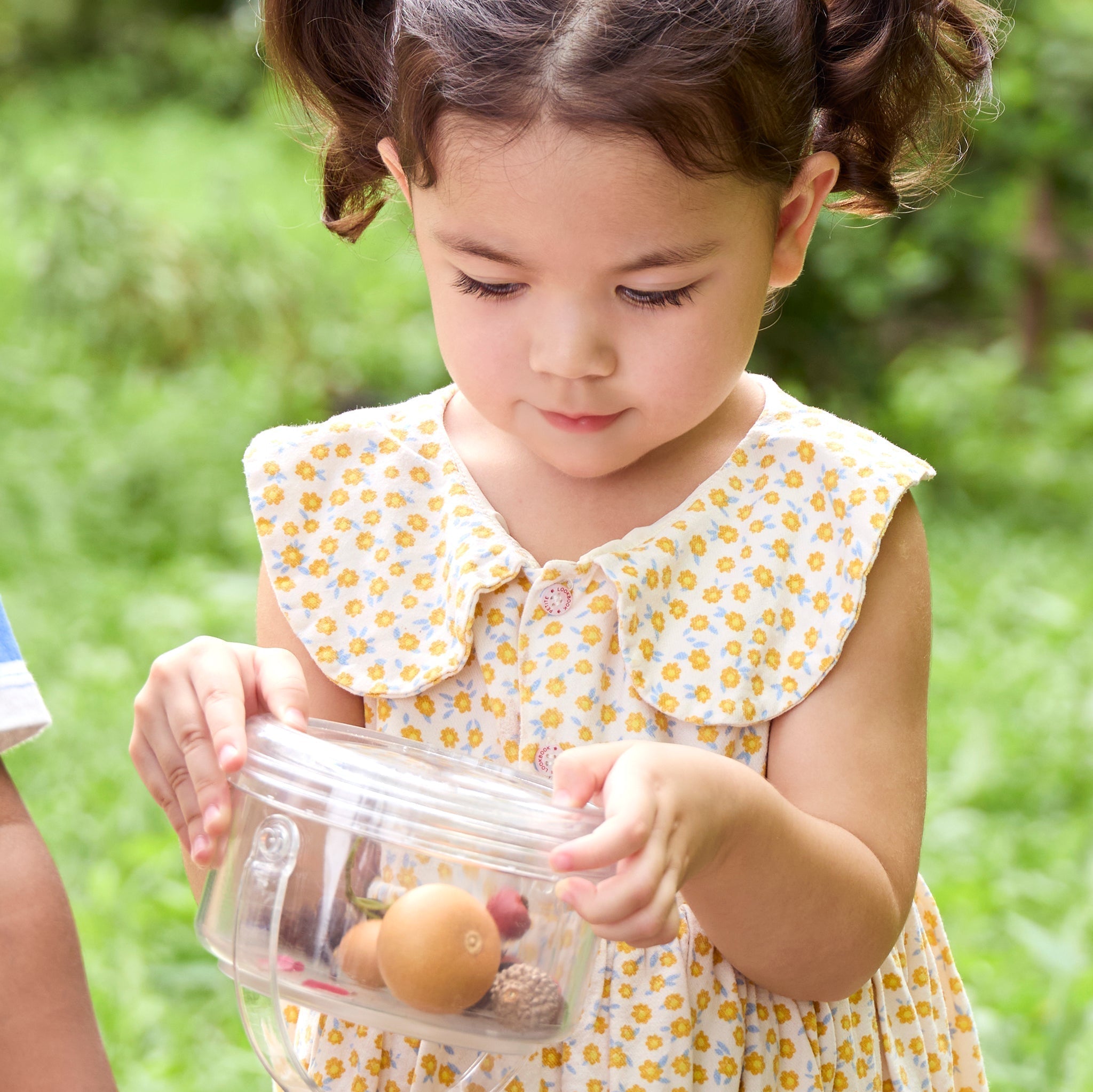 Little girl observing natural objects in a magnification container