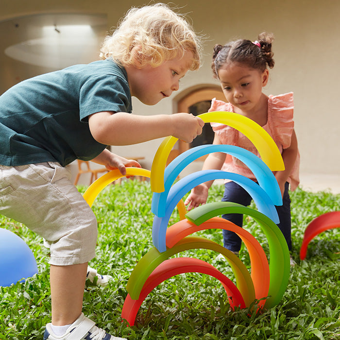 2 Preschool Aged Children playing with Guidecraft's colorful Discovery Arches and Tunnels Set