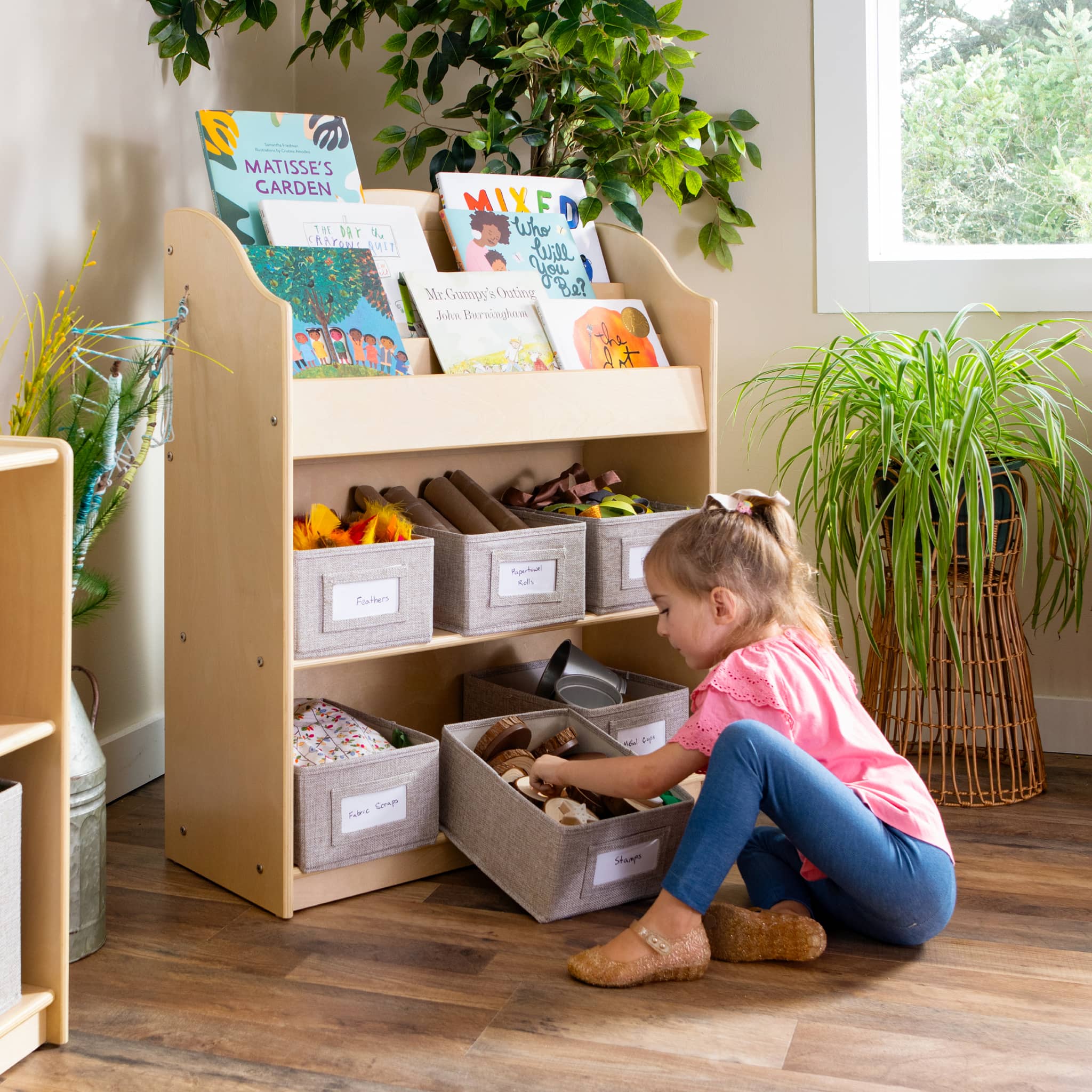 Girl getting toys out of the bottom shelf of a bookcase in a classroom