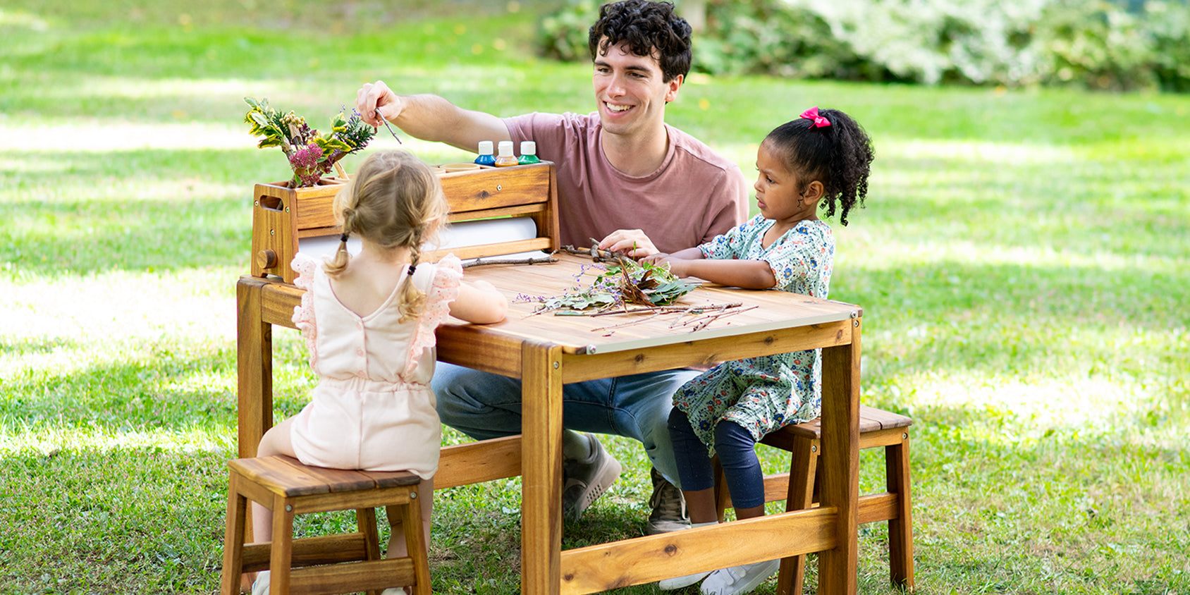Children and adult painting at an outdoor art table