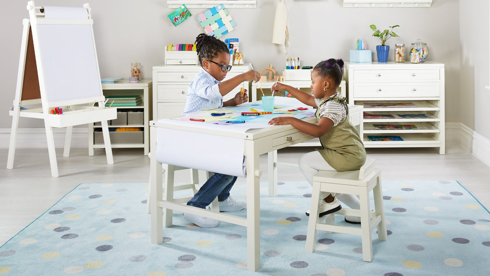 Two young children, a brother and sister, creating artwork at the white Martha Stewart Living and Learning Art Table