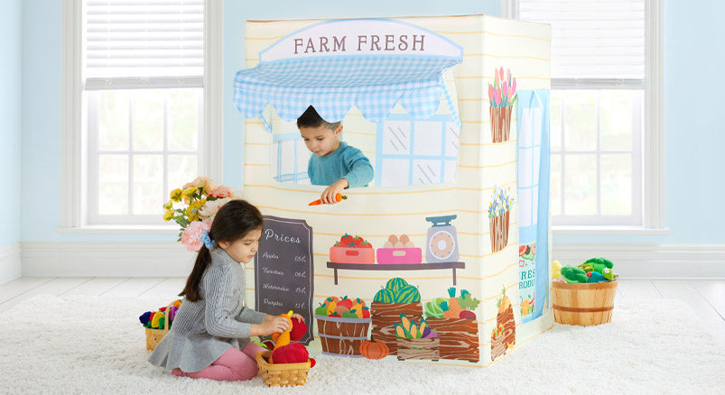 A young brother and sister playing with the Martha Stewart Fresh Market Playtent