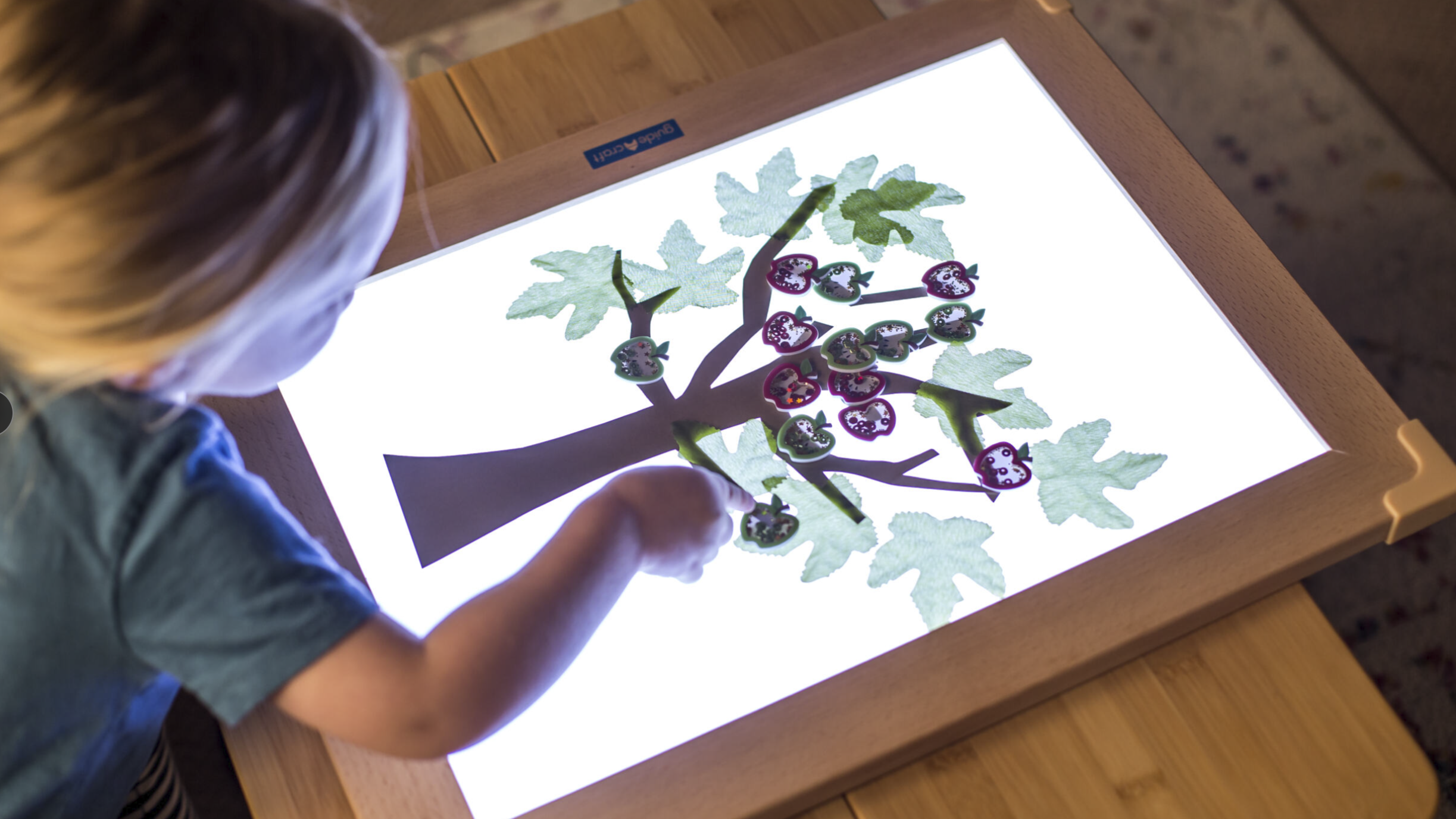 Young girl creating a tree on an LED light tablet