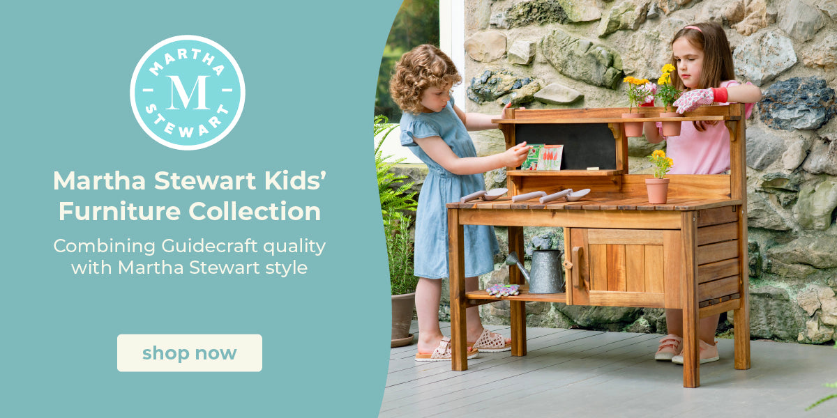 Two children playing with a wooden play kitchen set outdoors, with Martha Stewart Kids' Furniture Collection branding.