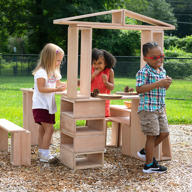 Children playing around a wooden playhouse in an outdoor setting