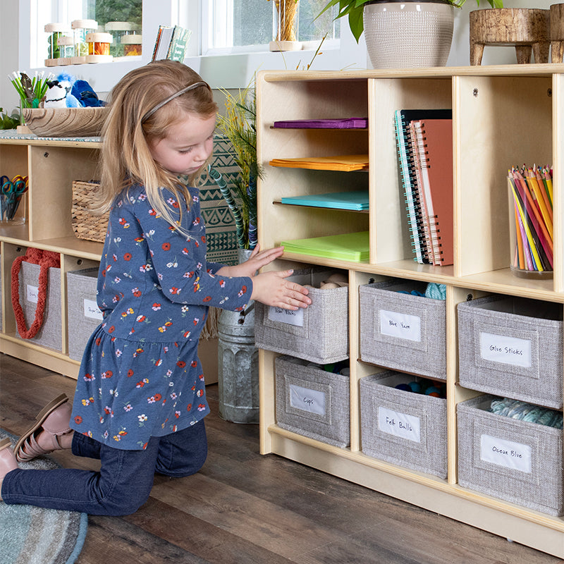 young girl pushing bin back into the 10 bin shelf