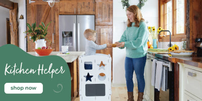 A woman and a young child stand in a bright kitchen next to a sturdy learning tower; text reads Kitchen Helper, shop now.