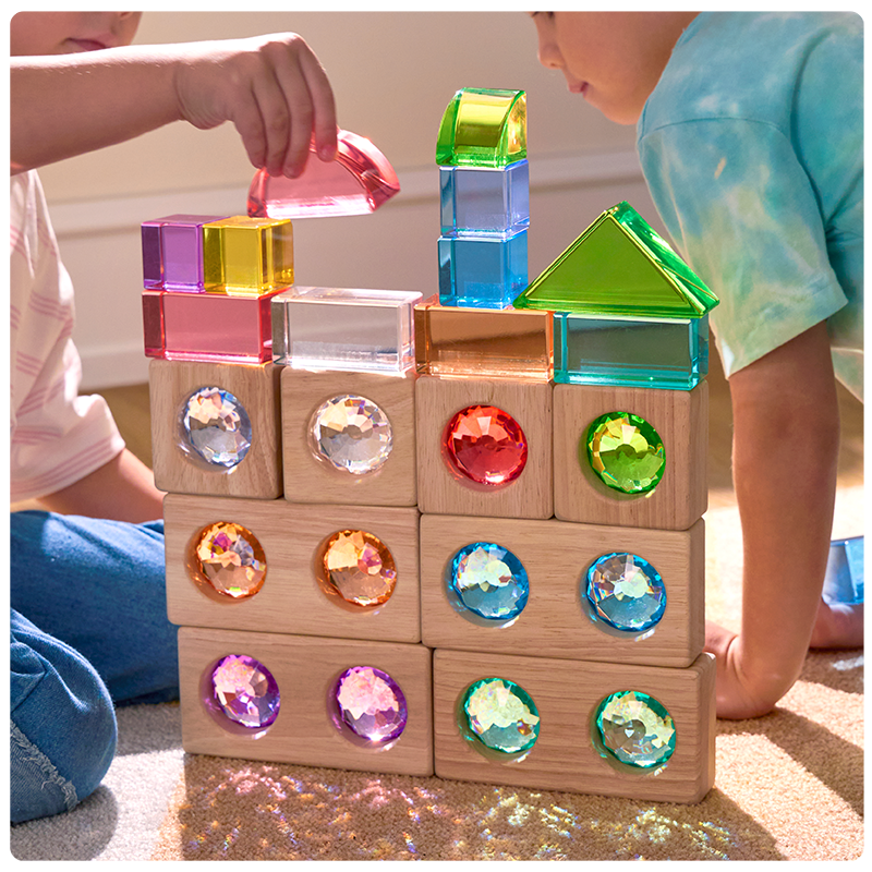 2 children building with a mix of colorful acrylic and wooden unit blocks to create a building structure