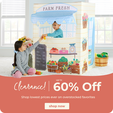 Children playing with a printed playset farm market hut labeled 'FARM FRESH' in a bright indoor room. The playset includes illustrated produce baskets, a chalkboard sign, and a blue-and-white awning.