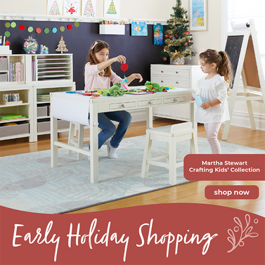 Two children playing at a Martha Stewart art table with craft supplies in a children's art room setting, featuring 'Early Holiday Shopping' text on a red banner.