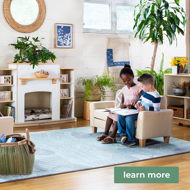 2 children sitting on a small couch reading a book together in a bright, clean, nature-filled classroom with calming blue, green and neutral touches. This is a banner for environmental classroom design services through Guidecraft.