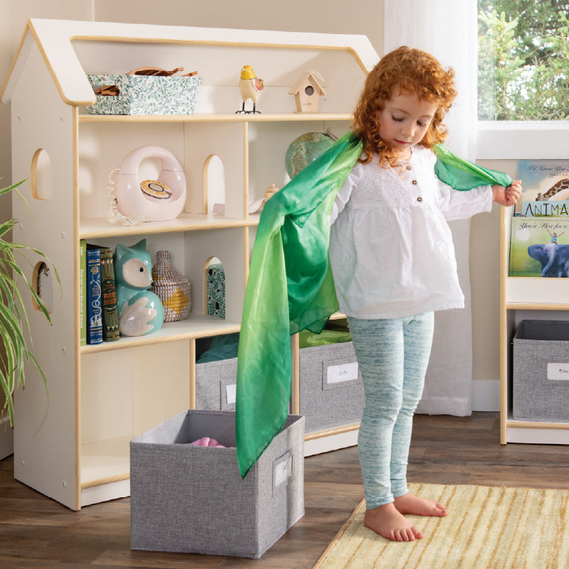 Young girl playing dress up in front of the EdQ Dollhouse Bookcase-Click to shop pretend play and dress up