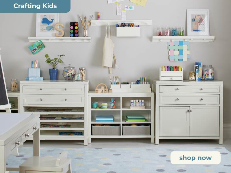 Children's art room with white furniture, shelves, and toys, featuring a 'shop now' button. Click to shop Martha Stewart Crafting Kids art furniture and supplies