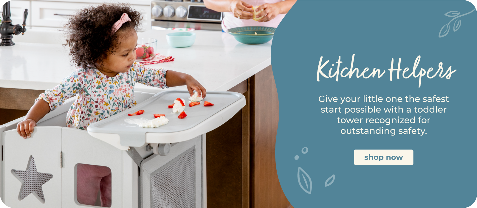 A toddler girl stands in a white high chair with a tray in a kitchen, reaching for strawberries on the tray. The right side features a large teal graphic with the text 'Kitchen Helpers' and a 'shop now' button.