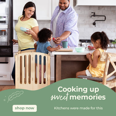 Happy family in the kitchen, youngest daughter in the kitchen helper toddler tower. Click to shop all kitchen helpers.