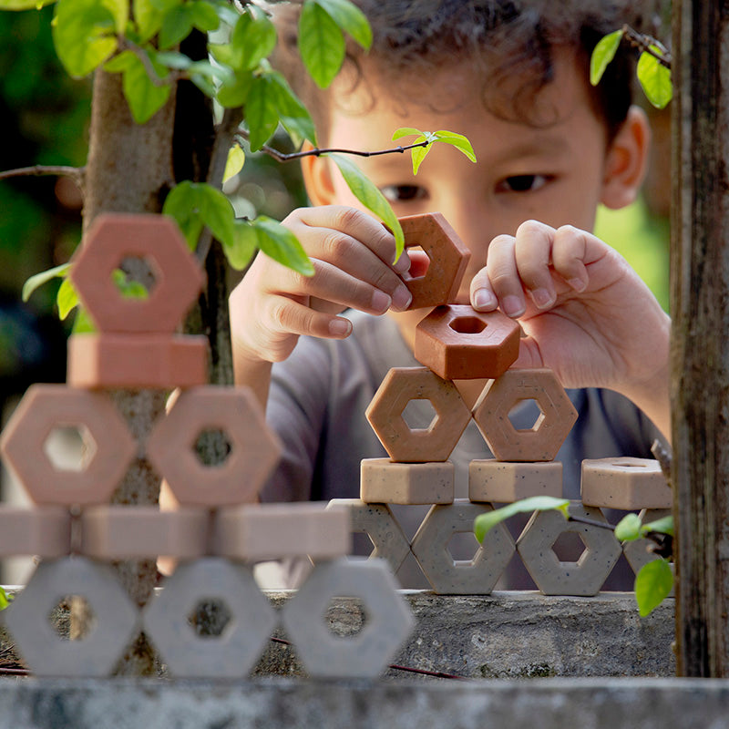 Close-up shot of a young child playing with Guidecraft's Little Paver toys outdoors