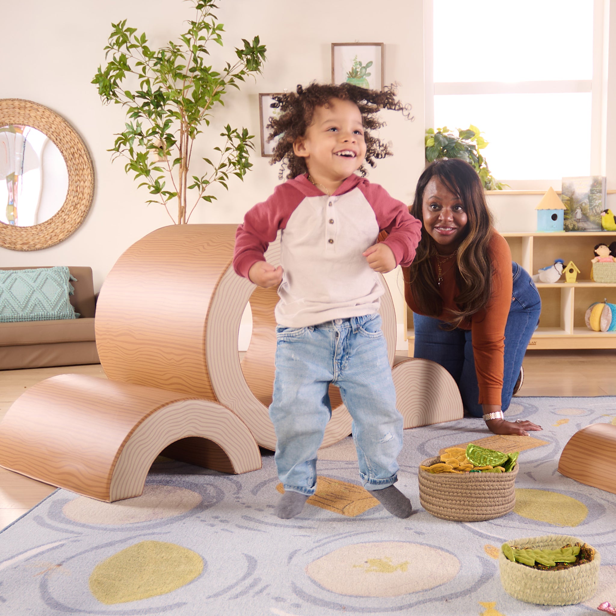 Child standing with a woman in a room with wooden furniture and plants