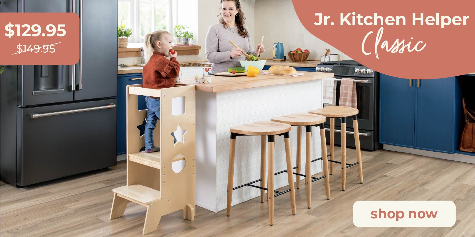 Mother and child at a kitchen island, child in a junior kitchen helper. Click to shop the Jr. Kitchen Helper Classic for $129.95
