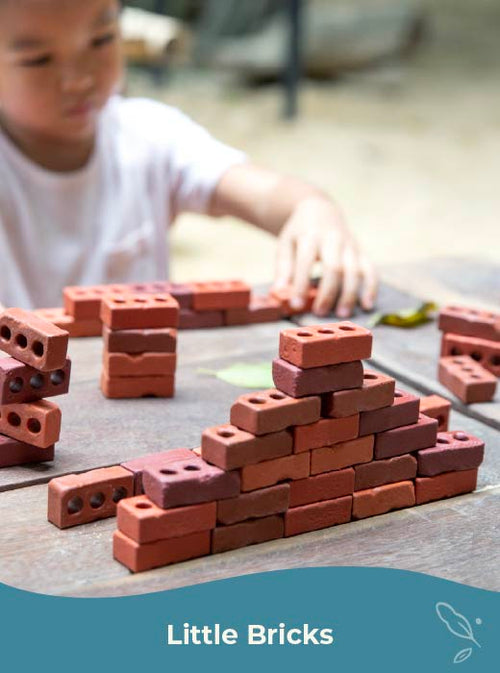 Child playing with red building blocks on a table. Click to shop little bricks building toy