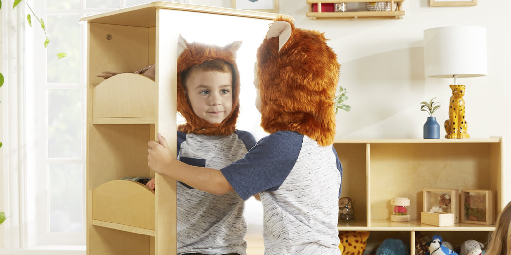 Little boy in fox costume looking in rotating dress up display-click to shop pretend play and dress up