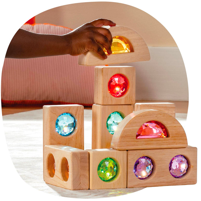 Wooden blocks with colorful gemstones being held by a hand