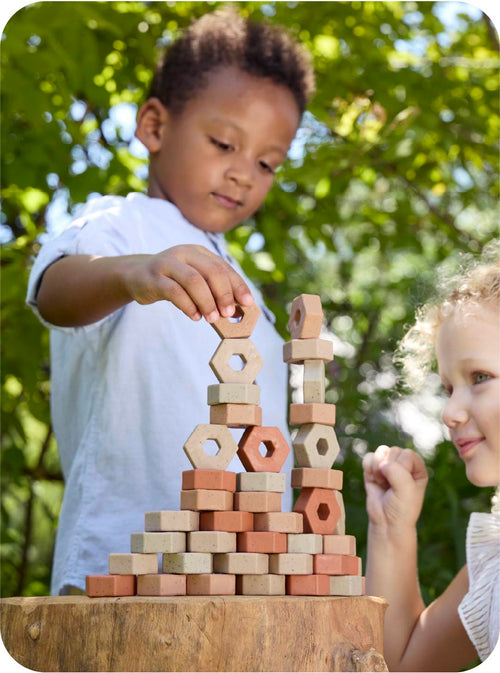 Two children playing with wooden blocks outdoors