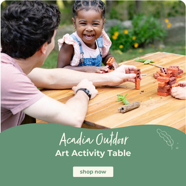 Person and child at a wooden table outdoors with Acadia Outdoor product promotion. Click to shop the Acadia Art Acivity Table