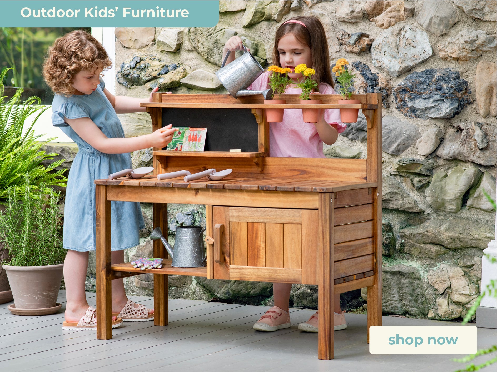 Two children playing with outdoor furniture against a stone wall.