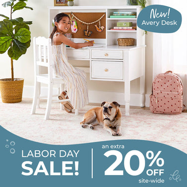 Child sitting at a white desk with a dog on the floor, promotional text for Avery Desk and  Labor Day Sale. Use code LABORDAY20 for 20% off everything