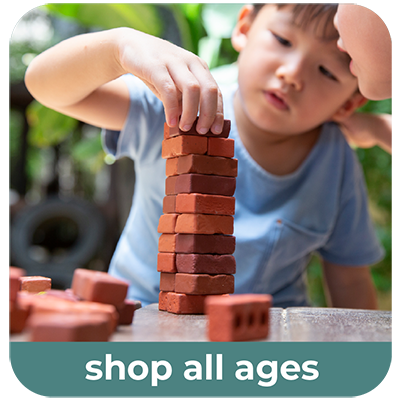 A child building a tall tower of Guidecraft's Little Bricks on a table, with a blurred outdoor background and a teal banner at the bottom reading 'shop all ages'.