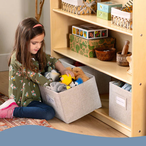 Child playing with toys in a storage bin next to a wooden shelf.