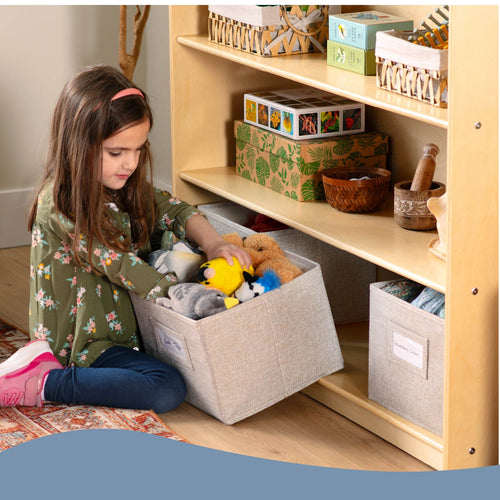 Child playing with toys in a storage bin next to a wooden shelf.