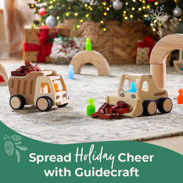 Wooden toys on the floor with a festive background, featuring Guidercraft branding. Click to shop block play and plywood trucks.