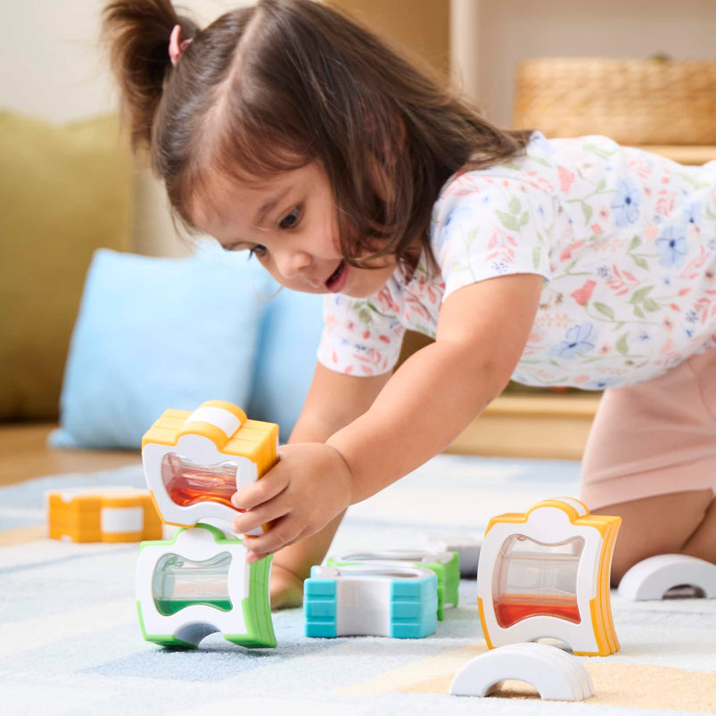 Child playing with colorful building blocks on a carpeted floor.