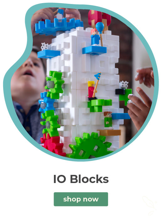 A promotional graphic for LEGO 10 Blocks featuring a circular photo of children building a colorful tower with white, blue, green, and red blocks. Below the photo, the text reads 'IO Blocks' and includes a green 'shop now' button on a white background.